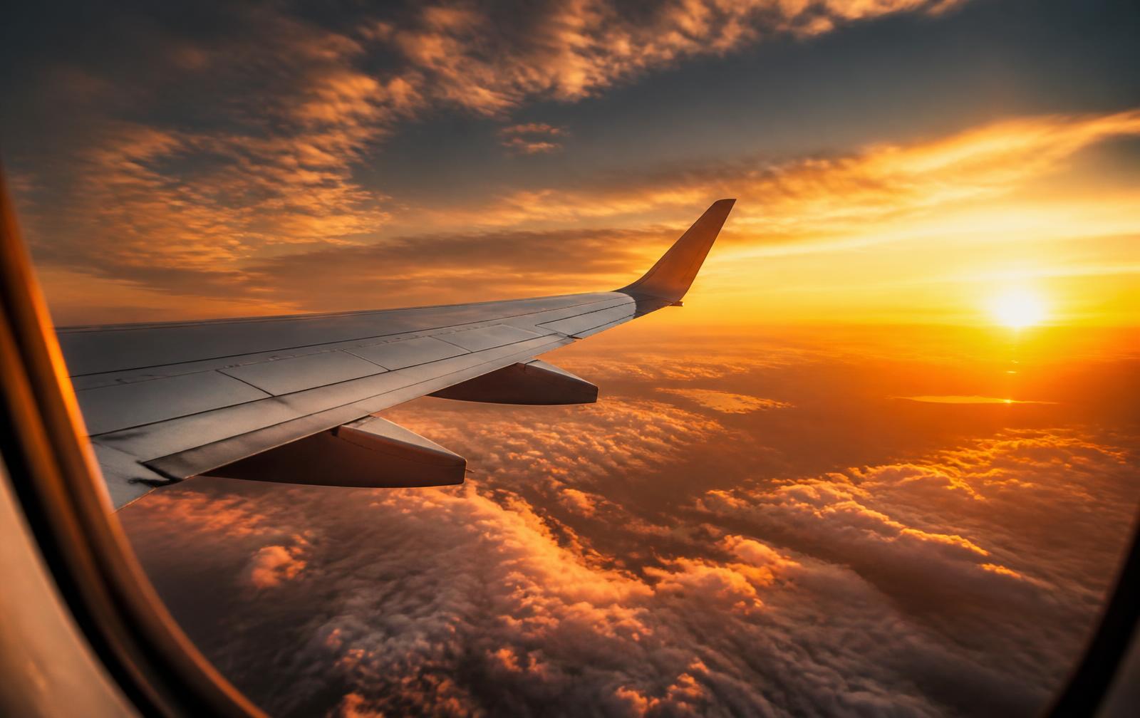 Ala de un avión comercial sobre las nubes al atardecer